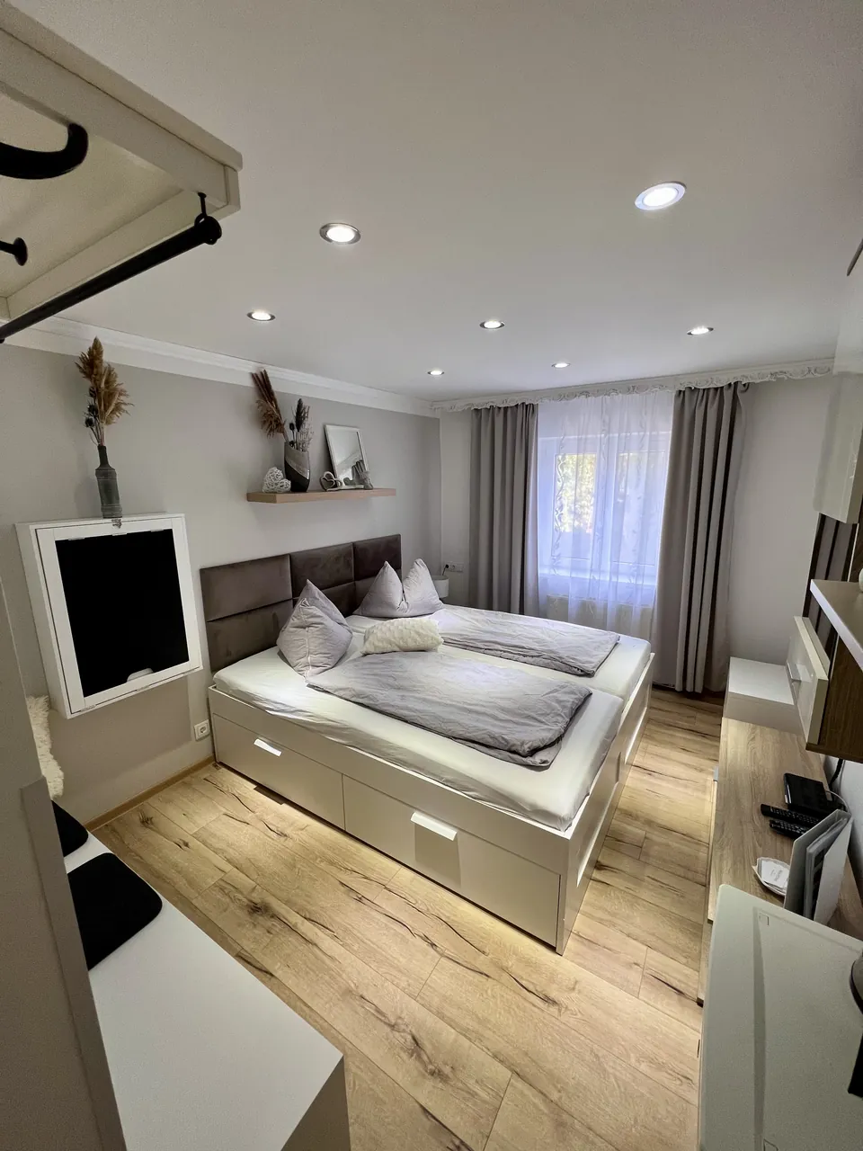 Doppelzimmer mit Queensize-Bett, grauen Vorhängen und Holzfußboden