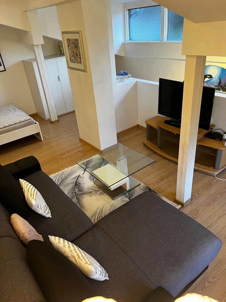 Wohnbereich der Maisonette mit Sofa, Glastisch und offenem Durchgang