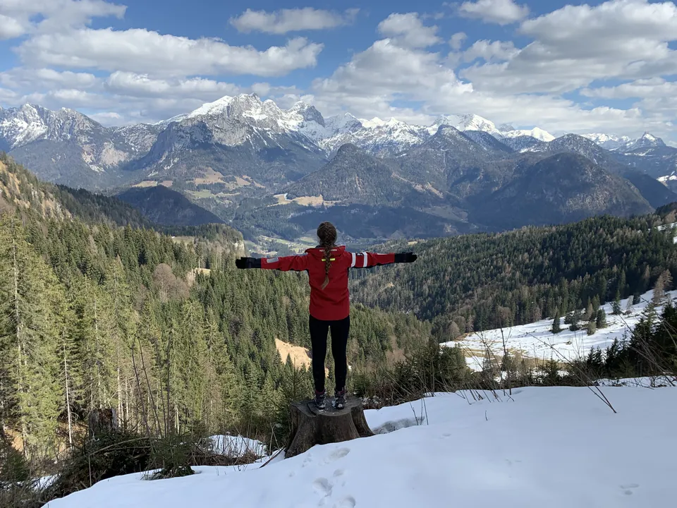 Wanderer vor der Bergkulisse auf einem teilweise verschneiten Hang
